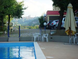 a swimming pool with an umbrella and chairs and a table and a umbrella at Hotel La Meridiana in Urbino