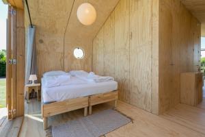 1 dormitorio con 1 cama en una pared de madera en Wikkelhouse, Kon. Emmaweg 6 Vrouwenpolder, en Vrouwenpolder