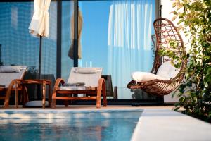 a pool with chairs and a hammock next to a table at Villa Dorra Coast Suites in Kanali