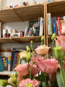 wazon z różowymi kwiatami przed półką na książki w obiekcie Feng Su w mieście Donggang