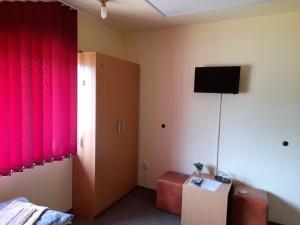 a room with a tv and a couch and red curtains at Casa cu flori in Bîrsău