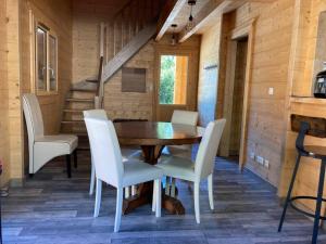 une salle à manger avec une table en bois et des chaises blanches dans l'établissement Forest Jura Lodge - Chalet des sapins, à Alièze