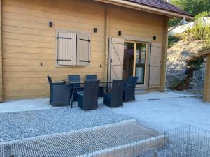 a patio with a table and chairs in front of a house at Forest Jura Lodge - Chalet des sapins in Alièze