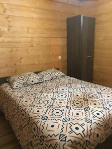 1 dormitorio con 1 cama con pared de madera en Forest Jura Lodge - Chalet des sapins, en Alièze
