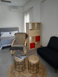 a living room with a bed and a couch and stool at Enalion residences in Tinos
