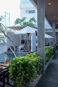 une personne assise sur un banc à côté d'une piscine avec un parasol dans l'établissement Dip & Doze Boutique Hostel, à Canggu