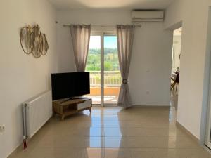 a living room with a flat screen tv and a window at Treditto House - 1st Floor residence in Koskinou