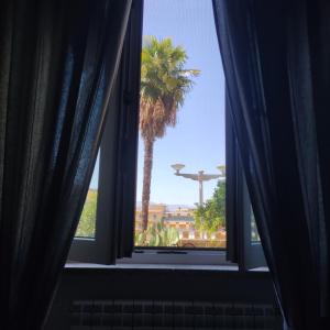 an open window with a palm tree in the background at Appartamento La Rampa in Benevento