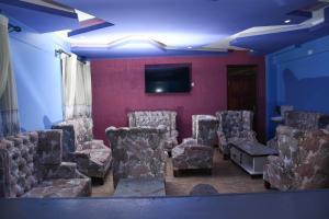 Habitación con sillas y TV de pantalla plana. en Golden Palace Hotel, en Eldoret