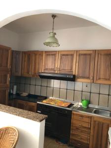 a kitchen with wooden cabinets and a black stove top oven at La Terrazza sul Mare in Sellia Marina