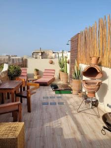 un patio con bancos, mesas y una valla en Riad Le Khan Mogador en Essaouira