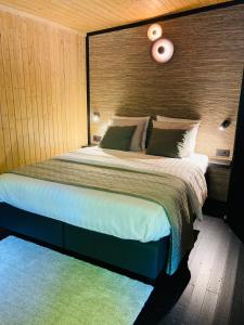 1 dormitorio con 1 cama grande y cabecero de madera en Ô NaNo Glamping, en Dalhem