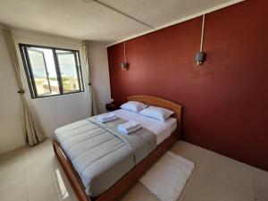 een slaapkamer met een bed met een rode muur bij Sunsetview Beach Apartment in Palmyre