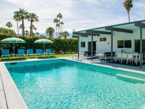 a pool with chairs and umbrellas next to a house at Alexander on Bedford in Palm Springs