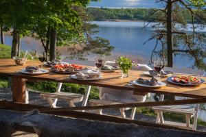a wooden table with plates of food and glasses of wine at Eremitstuga Detox resort in Köpmannebro