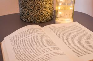 an open book on a table next to a candle at Adorable Country House with sea & church view! in Kokkini Khanion