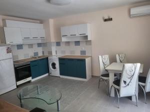 une cuisine avec des armoires bleues, une table et des chaises dans l'établissement Lucky Sun Kranevo Apartments, à Kranevo