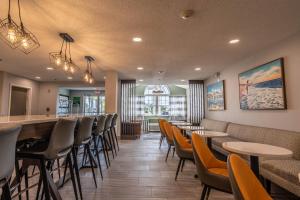 un restaurante con mesas y sillas y un bar en The Windstar Hotel - Carolina Beach, en Carolina Beach