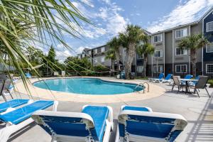 una piscina con sillas azules y un edificio en The Windstar Hotel - Carolina Beach en Carolina Beach