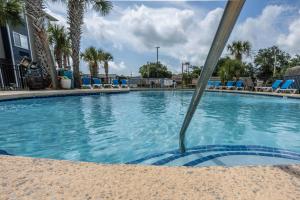 una gran piscina con sillas azules y árboles en The Windstar Hotel - Carolina Beach, en Carolina Beach