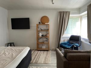 a bedroom with a bed and a chair and a tv at Little house with sauna in Lahti