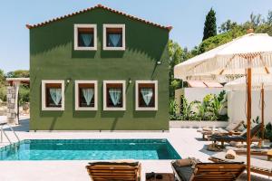 una casa verde con piscina y sillas en Stavlos Luxury Stone House, en Ialisos