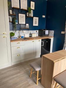 una cocina con armarios blancos y una pared azul en Lemonade cottages, en Kilmurry McMahon