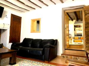 un sofá de cuero negro en la sala de estar en La Cabieda - Junto al Río Cañamares - ideal para grupos y familias, en Chilluévar
