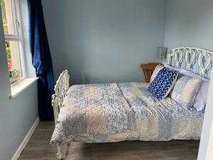a bedroom with a bed with a blanket and a window at Blueberry Tiny Home in Kilmurry McMahon