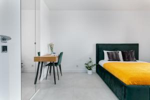 a bedroom with a bed with a yellow blanket and a desk at Pure Rental Apartments in Wrocław