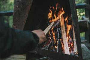 a person holding a stick over a fire at つながるキャンプリゾートQOONEL+ in Fujikawaguchiko