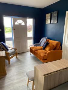 salon z brązową kanapą i niebieskimi ścianami w obiekcie Lemonade cottages w mieście Kilmurry McMahon