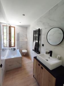 een badkamer met een wastafel, een bad en een spiegel bij BO LODGE in Le Bourg-dʼOisans