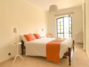 um quarto com uma grande cama branca com almofadas laranja em Supertubos Beach Villa em Atouguia da Baleia