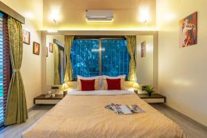a bedroom with a large bed with red pillows and a window at Coco Palms by VEO - Part of StayVista in Nashik +31 photos