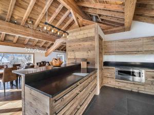 a kitchen with wooden walls and a large island at Chalet moderne à Méribel avec jacuzzi et sauna - FR-1-566-30 in Les Allues +2 photos
