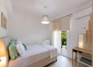 a bedroom with a bed and a desk and a window at Memoria Apartments by Imagine Lefkada in Lefkada