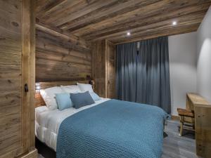 ein Schlafzimmer mit einem Bett in einem Zimmer mit Holzwänden in der Unterkunft Duplex spacieux pour 14 pers. avec sauna, terrasse et parking, au pied des pistes - Méribel Village - FR-1-566-11 in Les Allues
