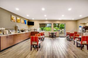 a dining room with red chairs and a kitchen at Comfort Inn Airport Roanoke in Roanoke