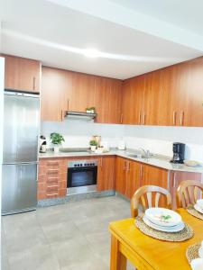 una cocina con armarios de madera y electrodomésticos de acero inoxidable en Almar Carril, en Vilagarcía de Arousa
