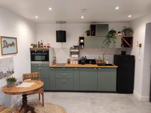 una cocina con armarios verdes y una mesa. en Superbe appartement avec jacuzzi avec jardin privé en Lyon