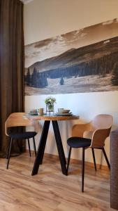 カルパチにあるApartament EverySky Karpacz - Wilcza 3aの絵画のある部屋にテーブルと椅子2脚