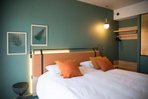 a bedroom with a white bed with two orange pillows at Campanile Saint Brieuc - Centre Gare in Saint-Brieuc