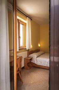 a bedroom with a bed and a desk and a window at Agriturismo la campagnola in Gordona