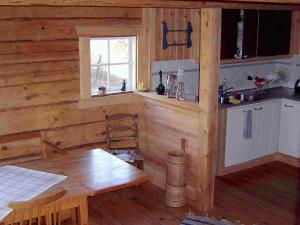 a kitchen in a log cabin with a table and a window at 8 person holiday home in VIMMERBY in Rumskulla