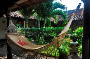 a hammock in front of a house with palm trees at Hotel Patio del Malinche in Granada
