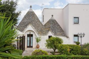 une maison blanche avec deux toits pointus dans l'établissement Hotel Ramapendula, à Alberobello