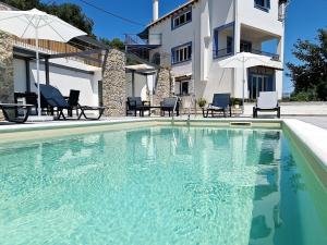 a swimming pool in front of a house at Ionian Juliet Villas in Kothoníkion