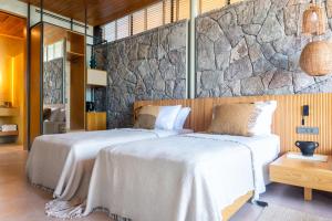 two beds in a room with a stone wall at Birdcage 33 Hotel - Adult Only in Yalıkavak +111 photos
