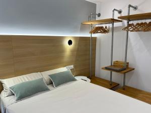 een slaapkamer met een wit bed en een houten hoofdeinde bij San Bernardo Apartamento de lujo con ascensor, Wifi y vistas a Collarada in Jaca